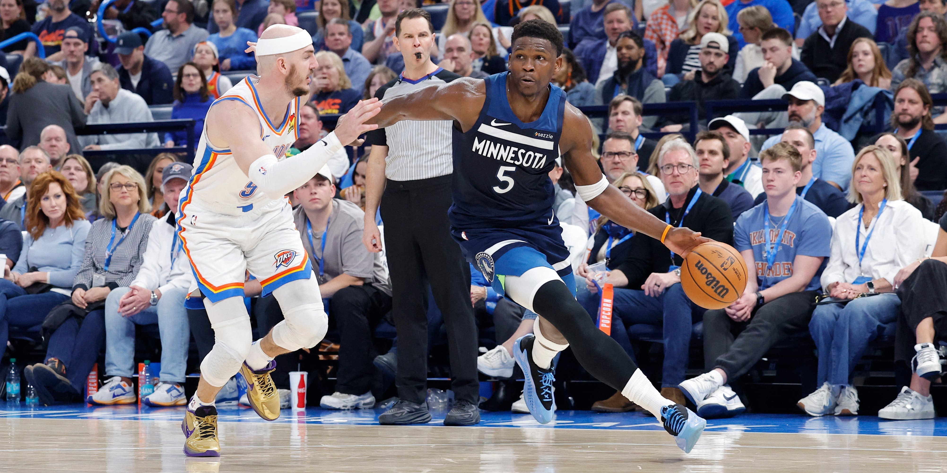 Minnesota Timberwolves guard Anthony Edwards (5) dribbles the basketball and drives around Oklahoma City Thunder guard Alex Caruso during a 2025 game.
