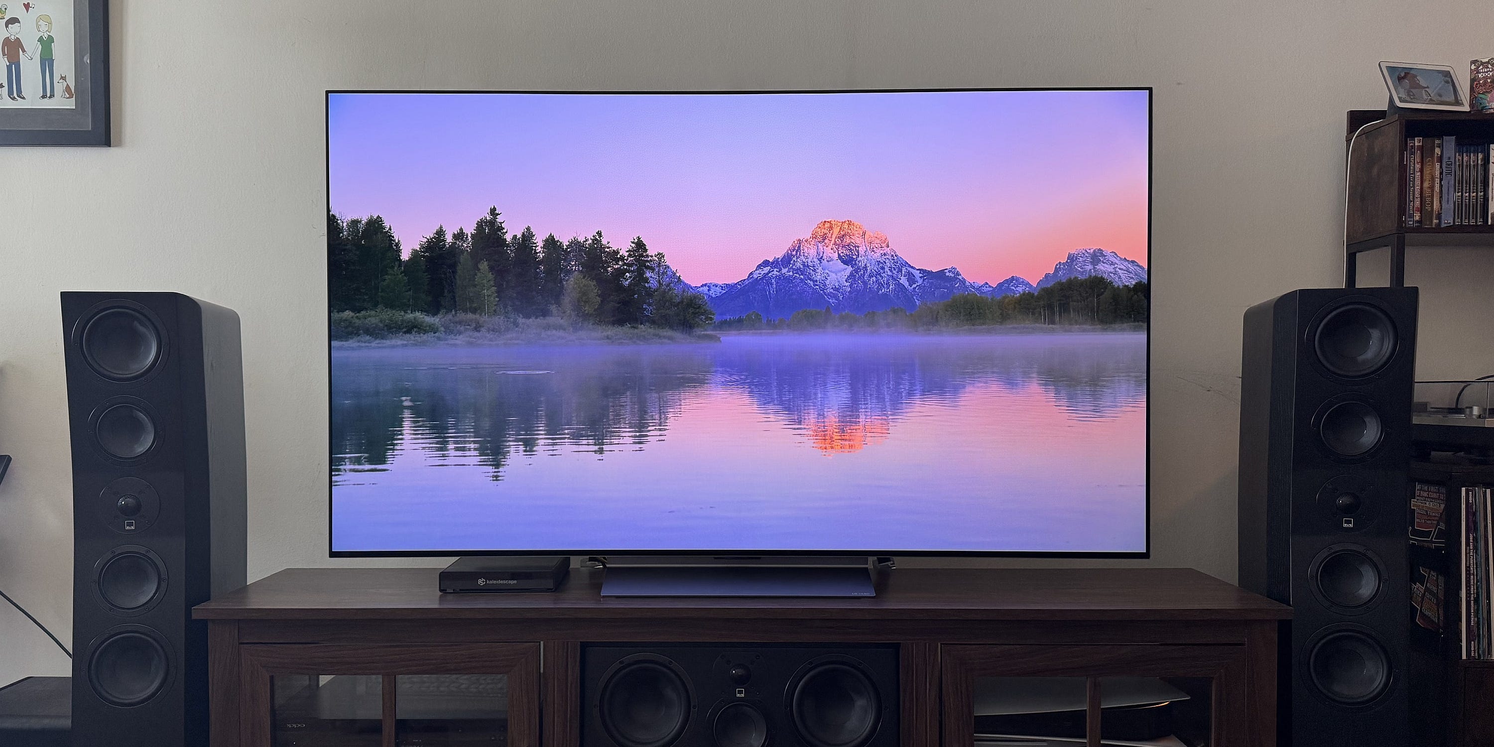 An LG C5 OLED TV on a media console between two floor-standing speakers.