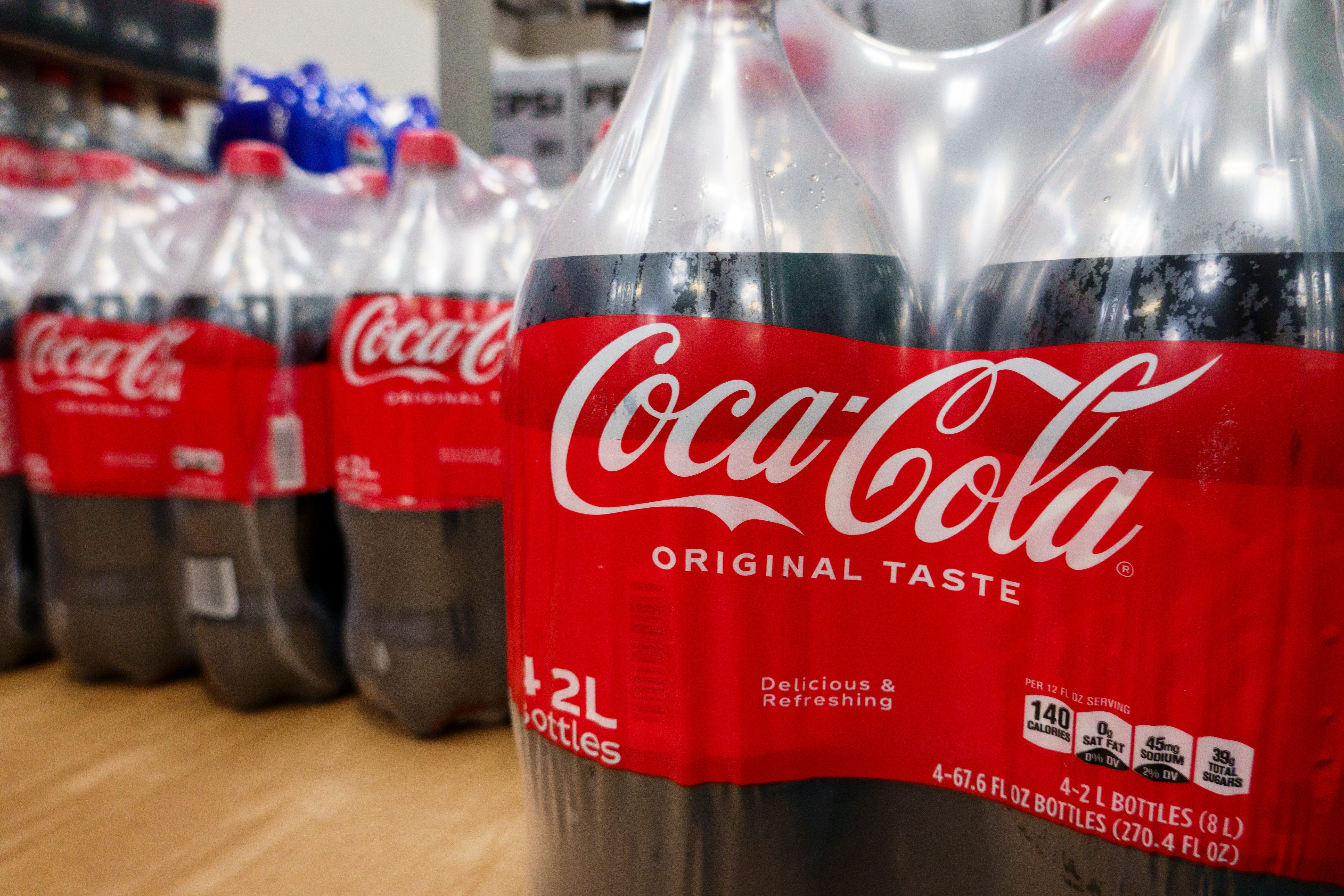 Two liter bottles of Coca-Cola soda, wrapped in plastic packaging
