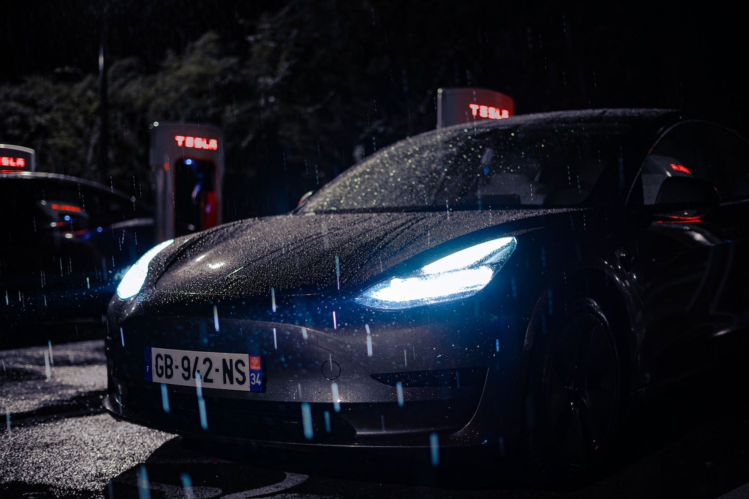 A Tesla at night with rain