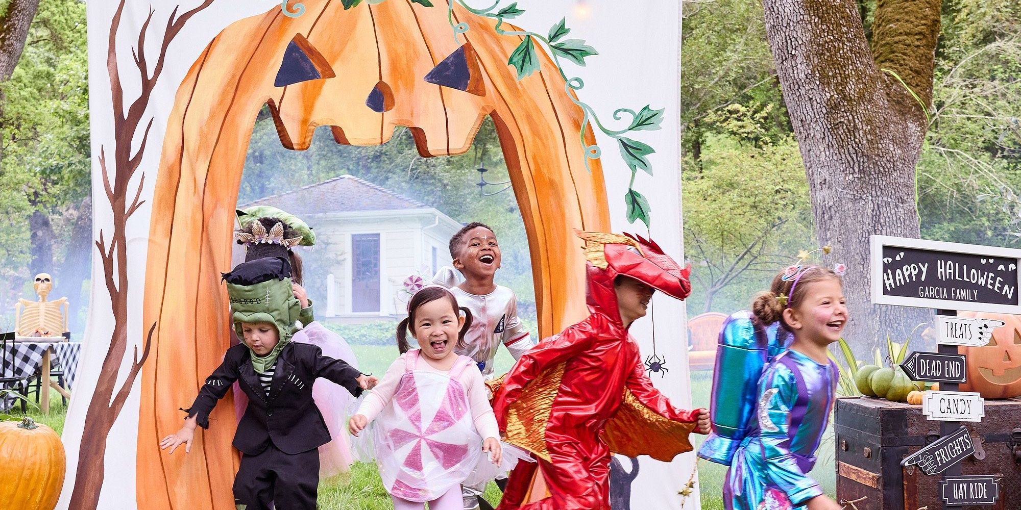 kids in costume running through a happy halloween pumpkin arch for pottery barn's halloween sale