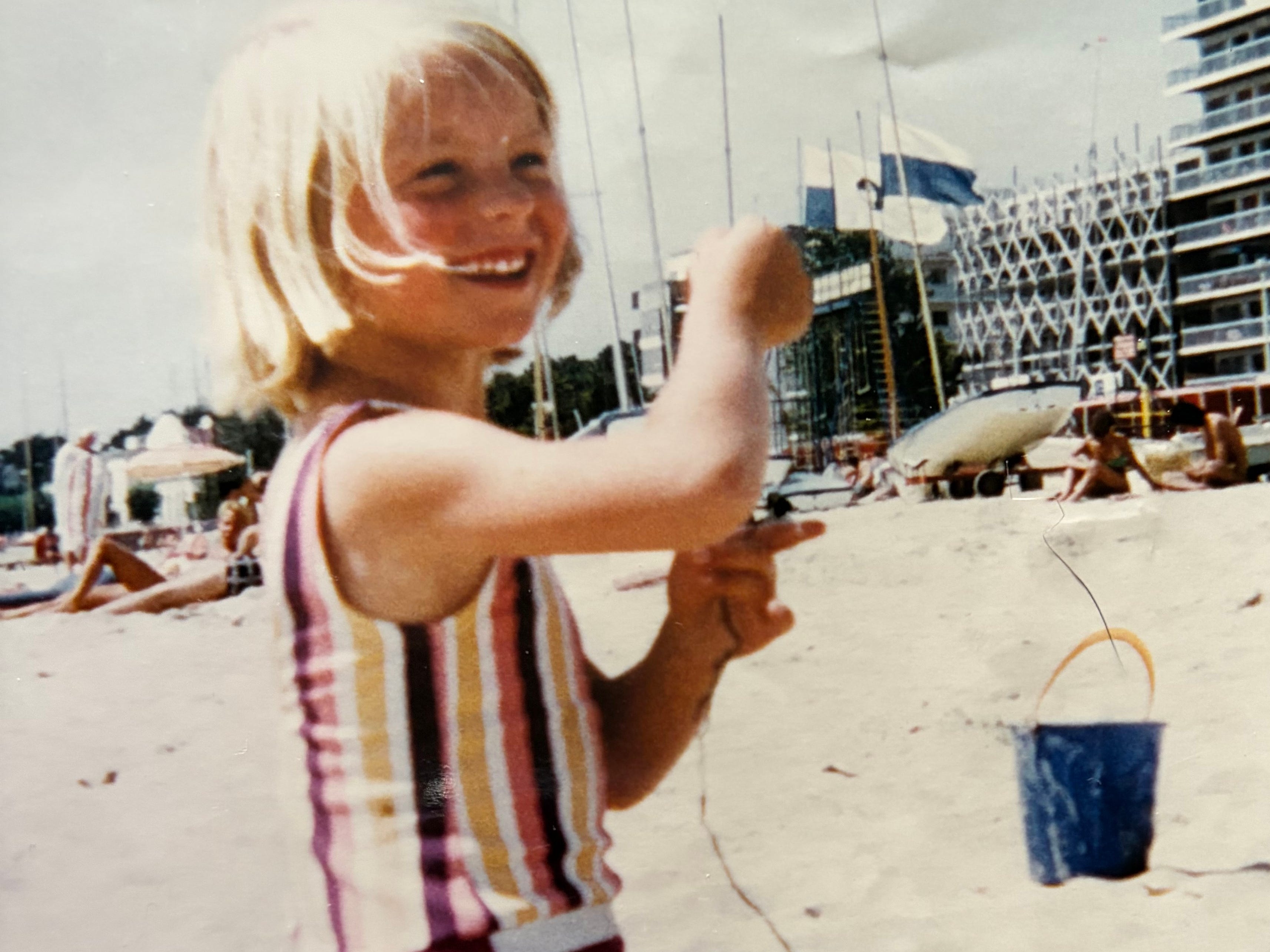 A little girl playing on a beach with a bucket and a spade.