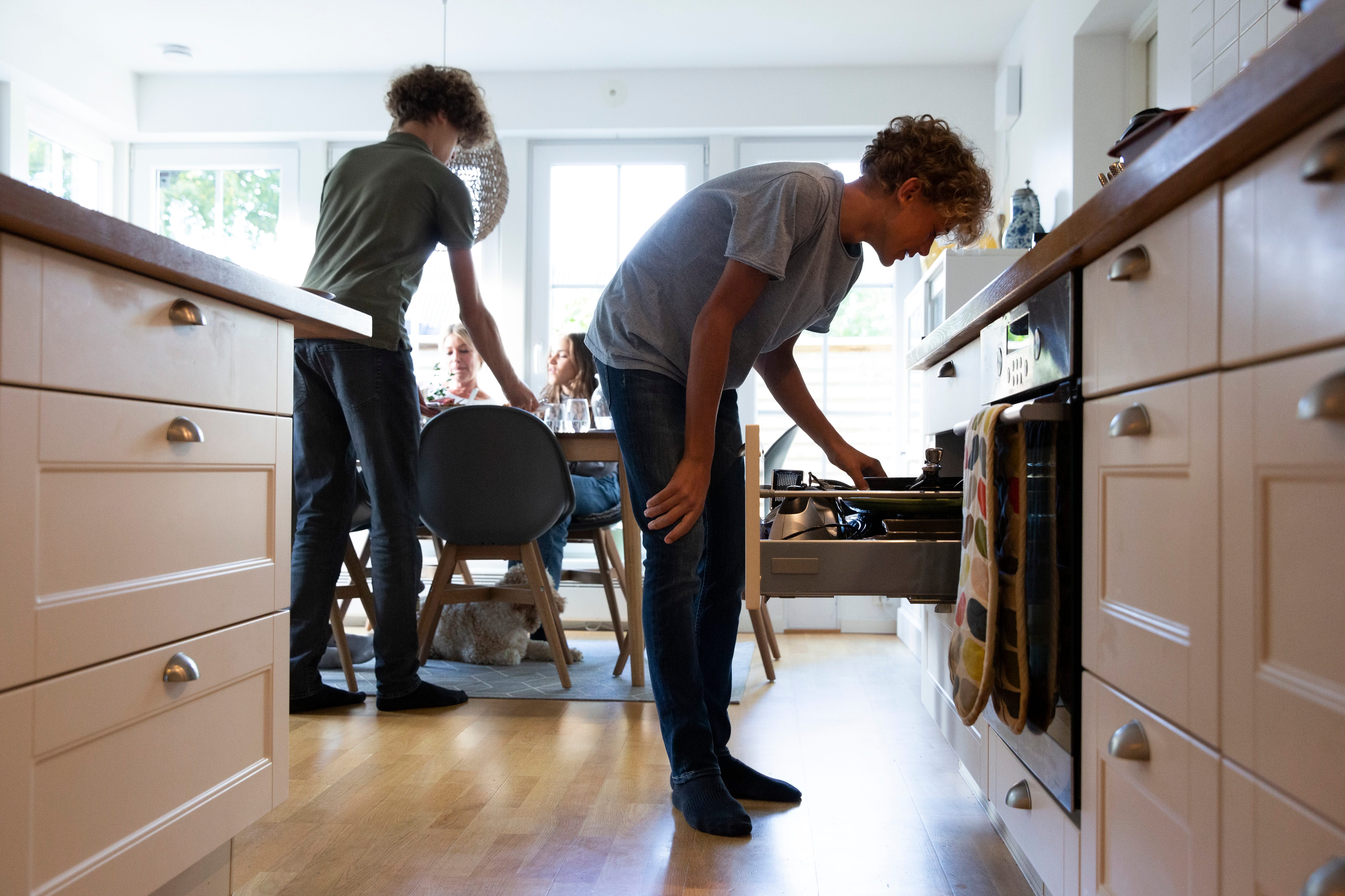 Boy searching in drawer while family at dining table