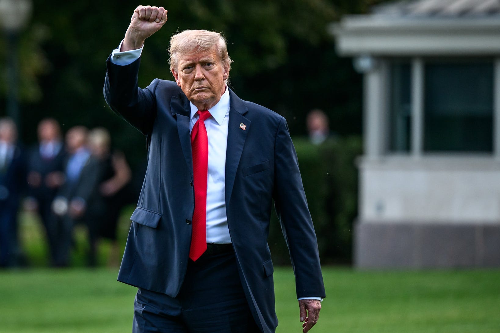 Donald Trump wearing a red tie with his fist in the air.