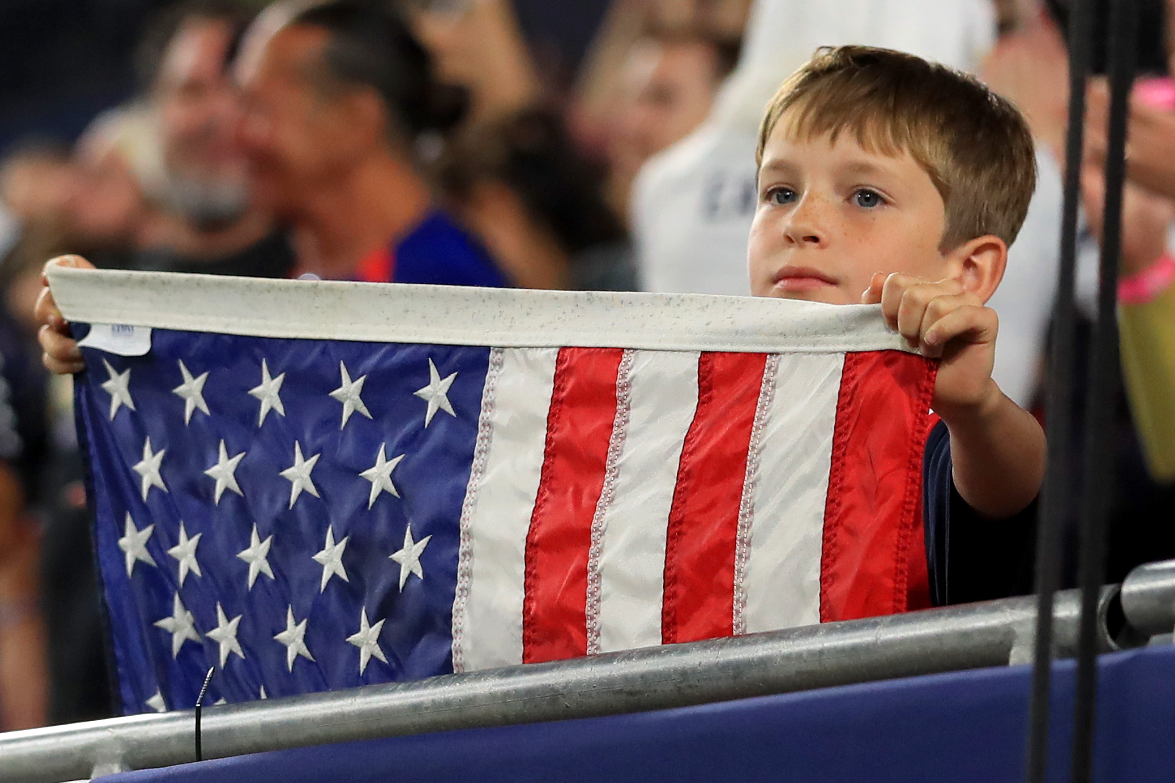A young boy holds an American flag at a soccer match