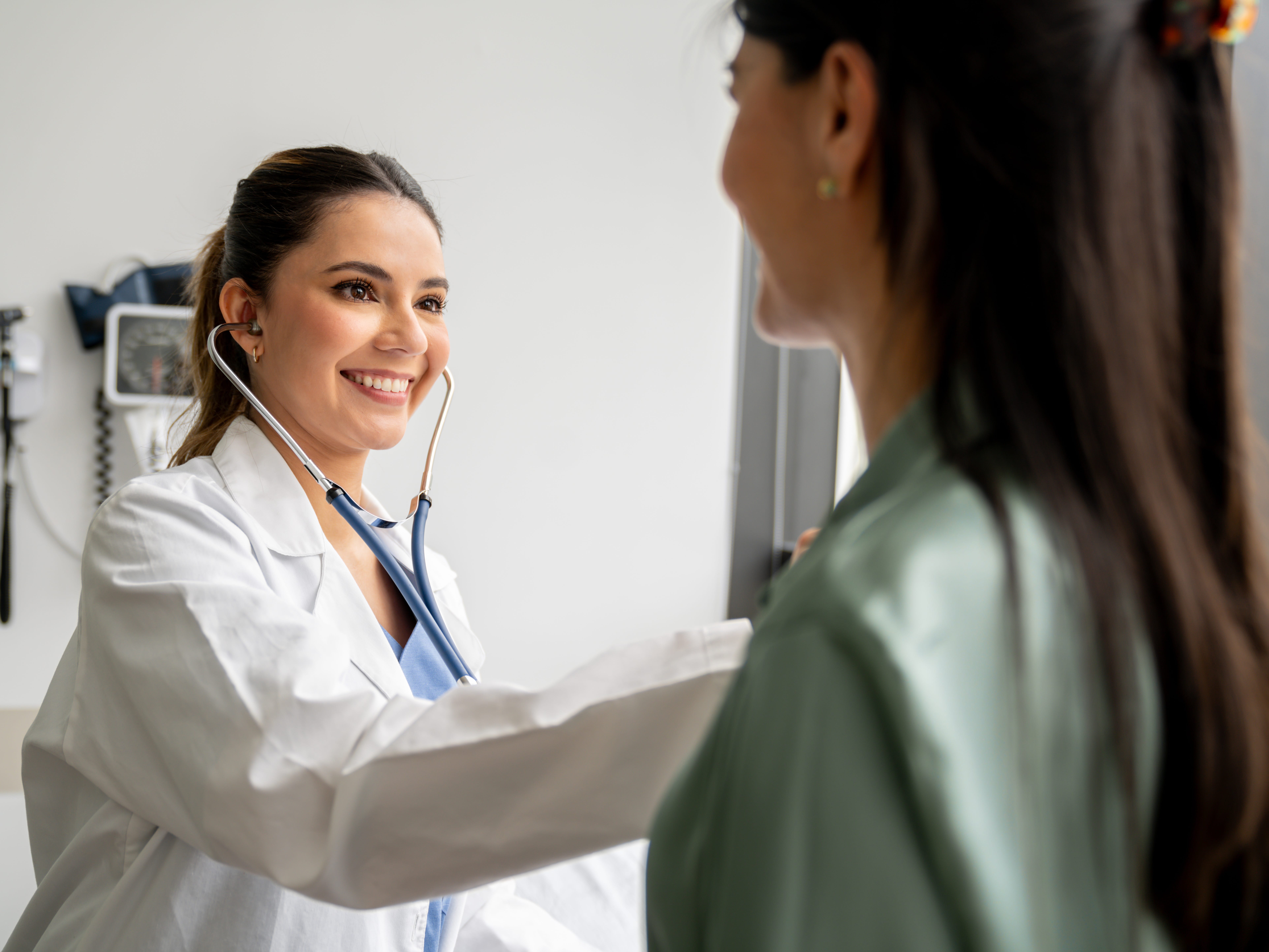 A healthcare worker with a stethoscope is listening to a patient