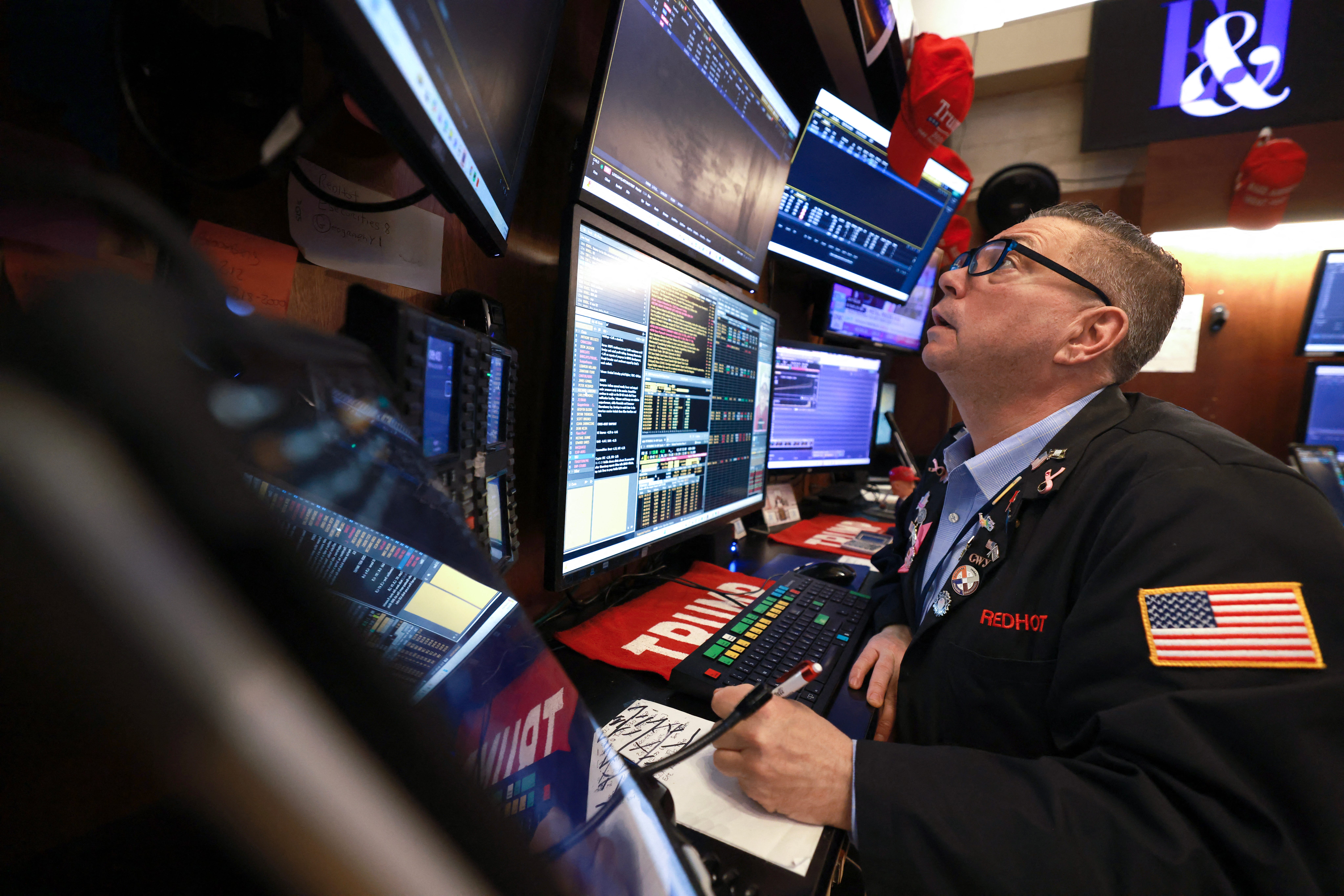 NYSE stock trader looking up at a screen at his desk