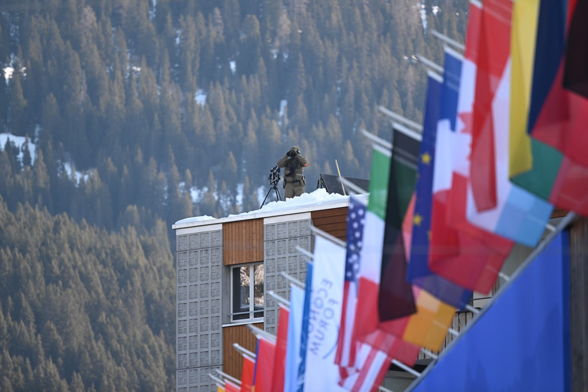 A sniper perched on a roof looks through binoculars at the World Economic Forum's annual meeting in Davos.