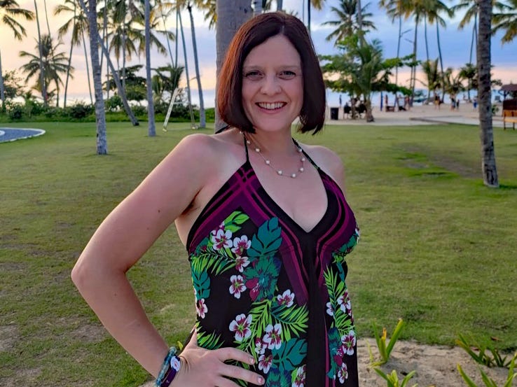 kari posing in front of a lawn full of palm trees in a tropical destination