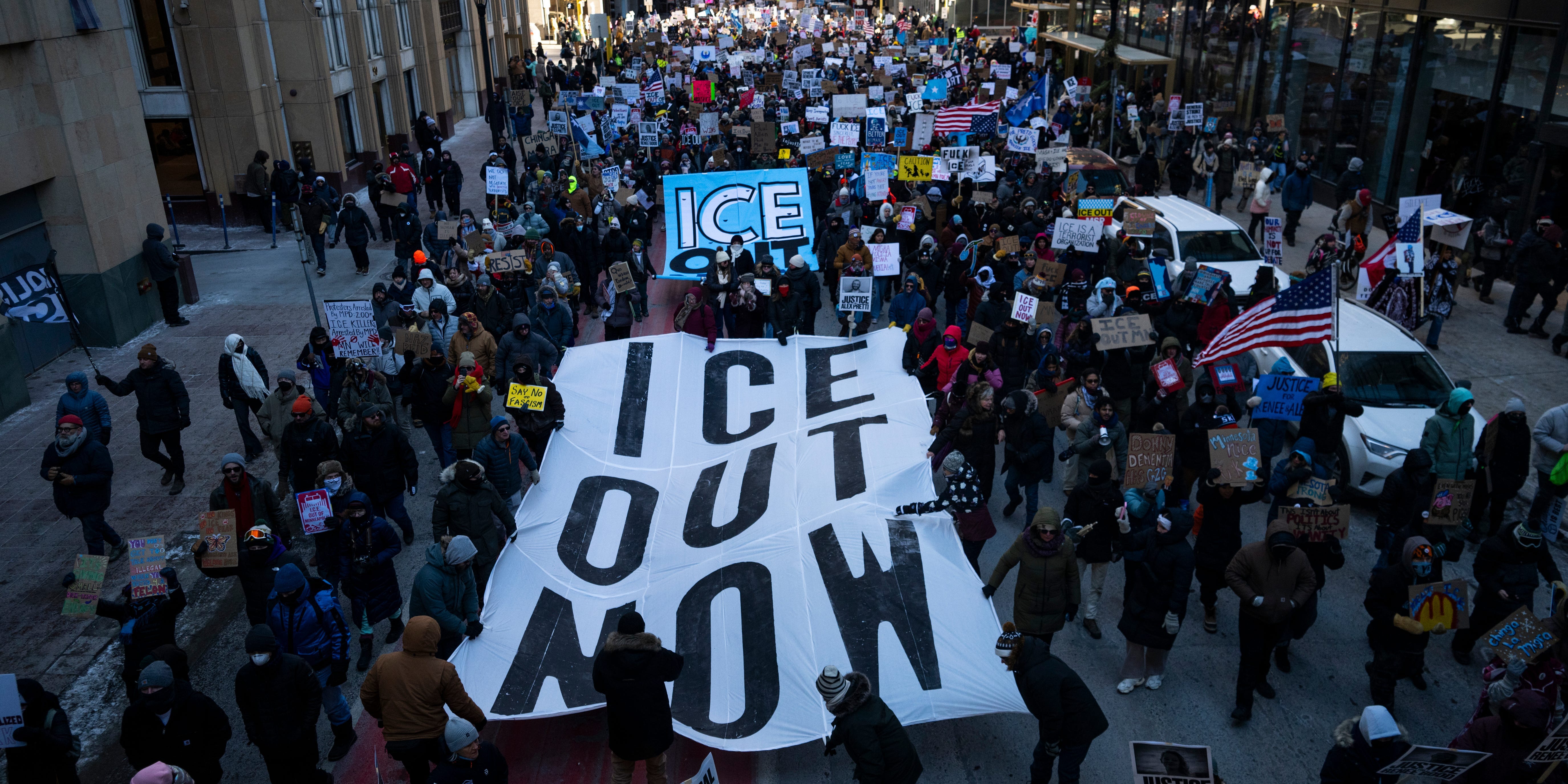 Protesters hold "ICE OUT NOW" signs
