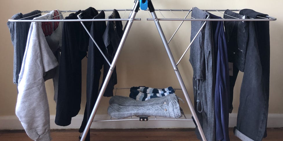 A clothes rack has several pieces of clothing hanging from it, including jeans and a sweatshirt.