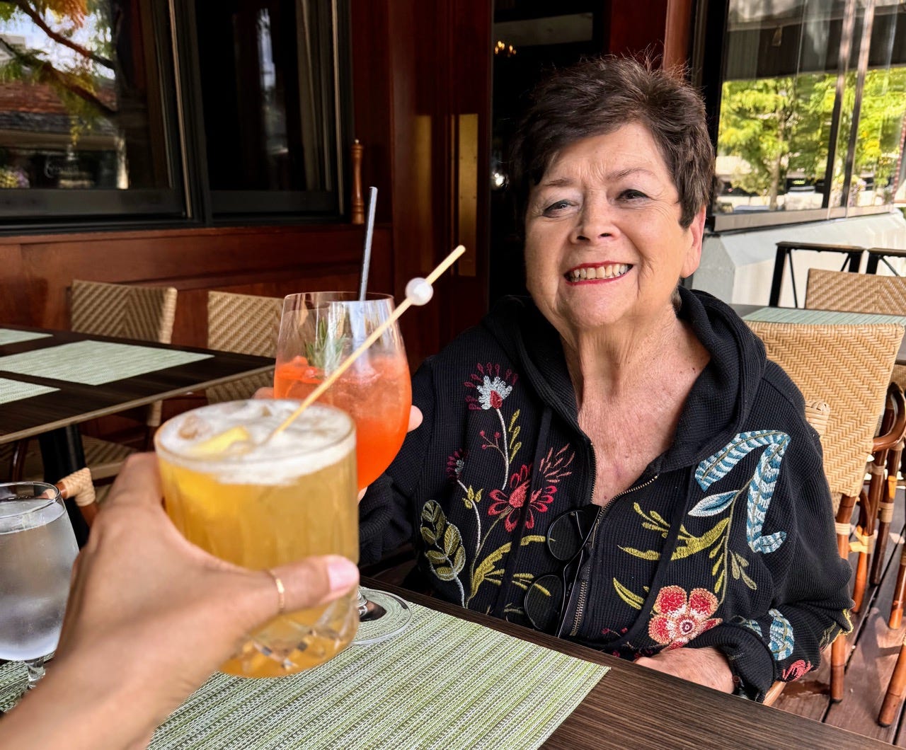 Woman cheersing drinks with someone at restaurant